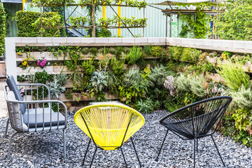 Garden chairs in a sitting area with vertical flower beds