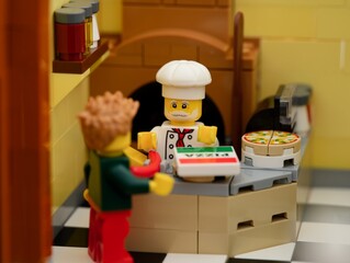 Fototapeta premium Tambov, Russian Federation - February 17, 2024 A Lego chef standing behind the counter and selling pizzas for customer in his pizzeria