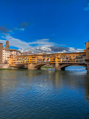 Obraz premium Ponte Vecchio bridge over the Arno River in Florence, Italy with blue sky reflecting on the river