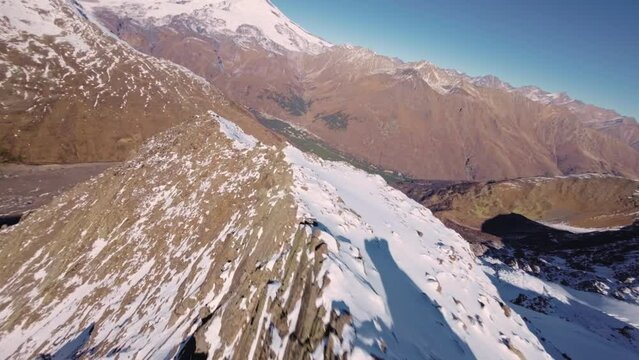 Dive from the top of a rocky mountain down under the rocks. Sport fpv drone flying over rocky mountain slope. Breathtaking footage of a dynamic fall from a cliff