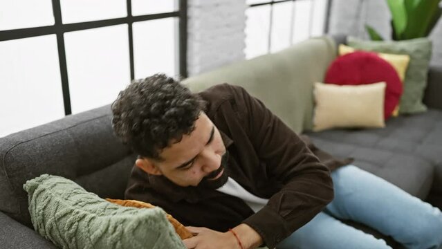 Young man wearing shirt sleeping tired dreaming and posing with hands together while smiling with closed eyes. at home