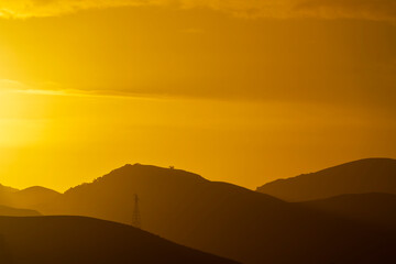 Orange sunset over silhouetted mountain horizon, at sunset, sunrise