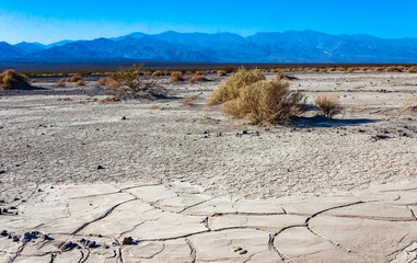 Dry yellow clay cracked in the sun with sand in the Californian desert, Death Valley National Park, California