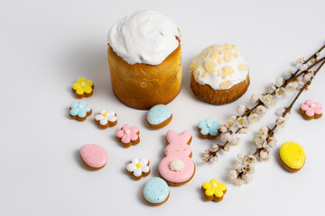 Easter cakes with Easter cookies and cherry blooming branches on white background