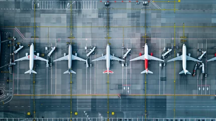 Fototapete An overhead view of many large passenger planes stuck on the tarmac of a large international airport. © cegli