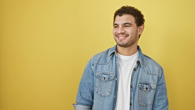Cheerful young arabian man with sparkling smile laughing confidently, glances aside, natural expression, standing isolated on vibrant yellow background