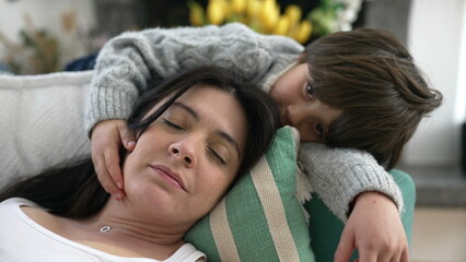 Son caresses mother while she rests laid on couch at home. Tender family relationship bond. Parent...