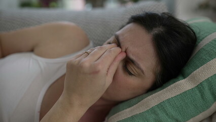 Stressed 30s woman close-up face laid on couch frowning putting hands in forehead struggles with...
