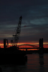 Obraz premium Silhouette of a crane and bridge during sunset