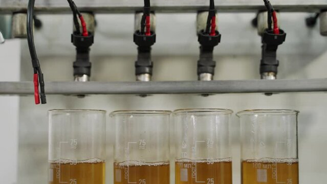 Fuel injector cleaning process in auto repair workshop. Car maintenance, precise auto part wash with ultrasonic tech, efficiency test. Fuel system care, garage service, engine optimization.