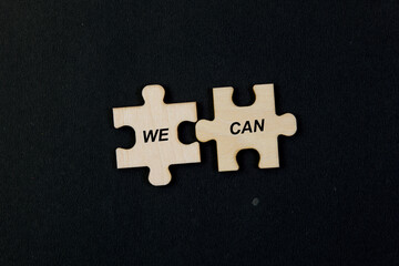 Puzzle pieces with word WE CAN Black background Business concept