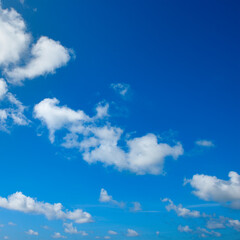 White fluffy clouds and bright sun on blue sky. - 783341422