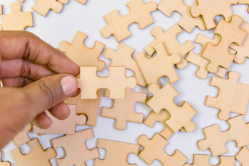 A closeup photo of a hand carefully positioning a jigsaw puzzle piece