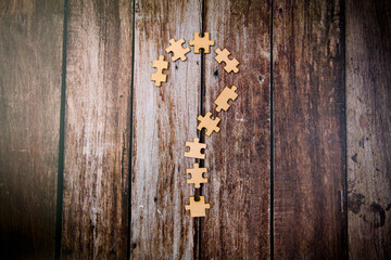 Question mark made of wooden puzzle pieces on old wooden background business  concept
