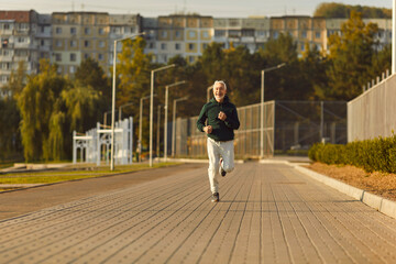 Mature sporty male runner jogging in city park. Healthy sporty fitness man running outdoors...