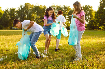 Fototapeta premium Group of teenage children volunteers with gloves and trash bags collecting garbage in the summer park outdoors. Kids boys and girls cleaning environmental pollution. Ecology concept.