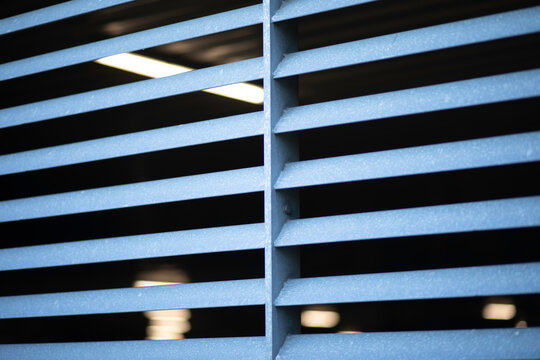 Matel barriers, car park fence, blurred lights inside the building in the background. 