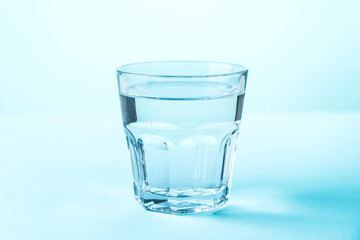 Glass of water on blue background. - 783348456