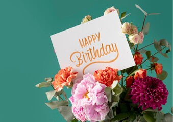 A close-up photo of a happy birthday card leaning against a vibrant bouquet of colorful flowers. The card has a bold, pink message that says "Happy Birthday"
happy birthday card with flowers 