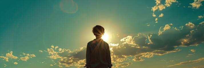 A meditative image of a person facing the sun, their form backlit by a majestic sunset and vast cloudscape