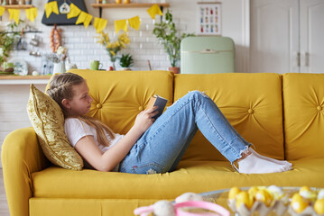 Girl 12 years old, lying on the sofa in the living room and reading a book