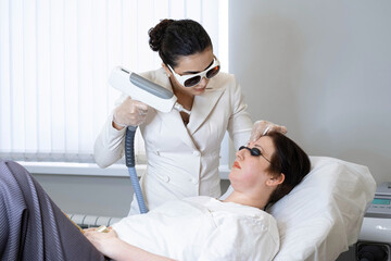 Aesthetician performs laser therapy, patient relaxed with goggles. Image taps into beauty trends...