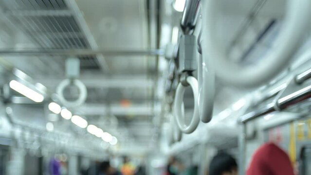 Close-up shot of the handrail with passengers crowding the electric commuter train as it stops at one of the stations in Jakarta Indonesia in the afternoon, some of them standing and others sitting
