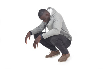 side view of man squatting and looking down on white background
