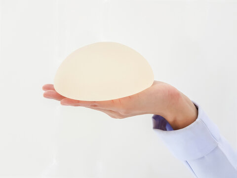 Silicone implant breast rough skin on the palm or hands, white background.