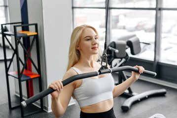 Fototapeta premium young athletic caucasian woman trains in fitness gym, doing thrust of upper block to chest, blond girl in white top and black leggings, healthy lifestyle concept