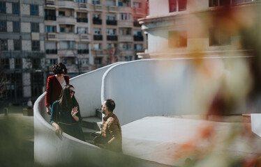Three business colleagues engage in a conversation outdoors on a sunny day with a cityscape in the...