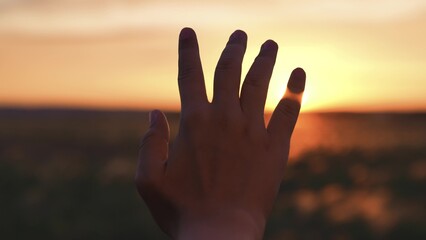 Woman stretched out hand sunset silhouette. Girl traveler in field dreams prays contemplates...