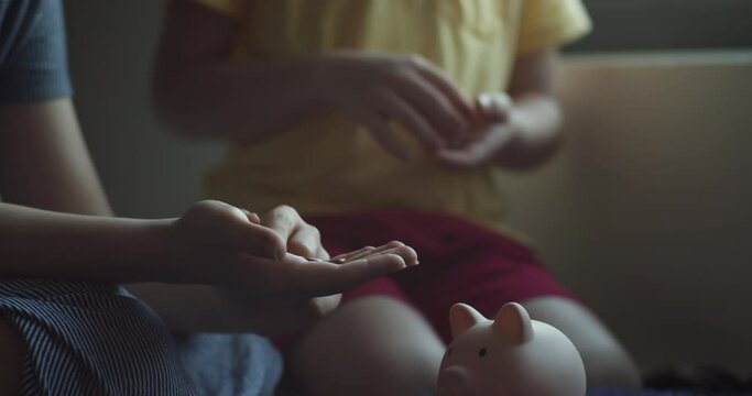 Children throw coins into a pink pig piggy bank. Coins in a piggy bank symbol of banking security. Financial savings are kept in bank. Concept of children preparing for business and financial security