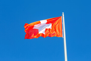 Flag of Switzerland flying in the wind against a blue sky - 783370670