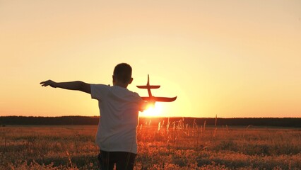 boy runs with plane his hand, child boy plays with toy plane, child son runs happily through field sunset, fantastic dream airplane pilot, cheerful child boy runs happily with toy plane through park