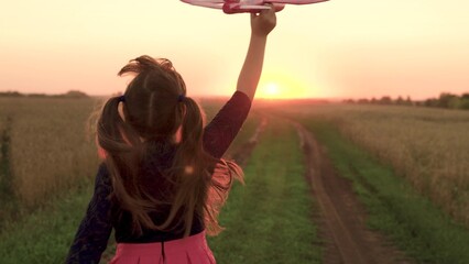 girl plays countryside toy airplane, girl hair flutters wind while running airplane sunset, child...