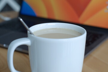 cup of coffee with milk with laptop on background