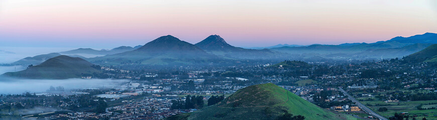 Panorama of valley, city, hills, mountains at sunrise sunset