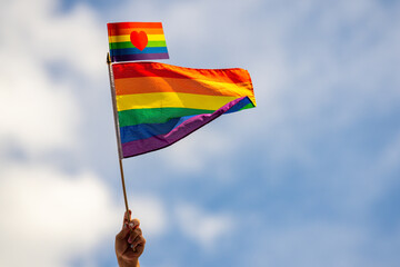 Hand holding rainbow gay flag, symbol of lgbt people, diversity of genders love. Lgbtq community pride month. Flag lgbt. Gay pride parade. Pride month. - obrazy, fototapety, plakaty