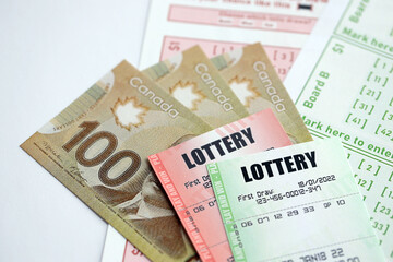 Lottery tickets lies with canadian dollars on gambling sheets with numbers for marking to play...