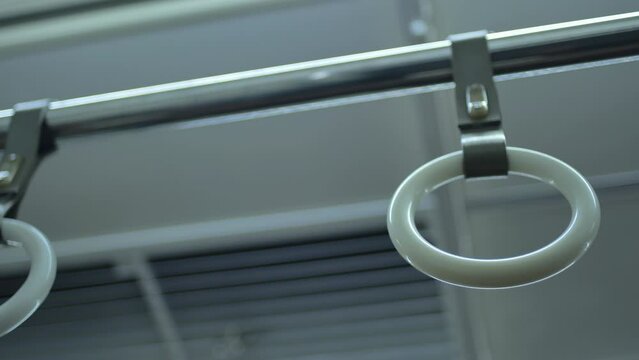 Panning shot of the empty handrails of an electric commuter train as it stops at a station in Jakarta, Indonesia, during the day