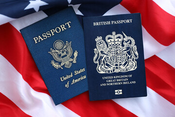 Passport of Great Britain with US Passport on United States of America folded flag close up