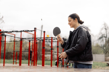 playing ping pong. A woman plays amateur table tennis on a public tennis table in the middle of a...