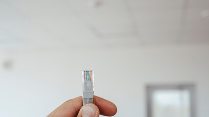 LAN ethernet cable in hand. Gray RJ45 twisted pair cable for computer network. Cat 5e UTP...