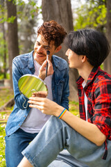 Two gay men applying make up in a park