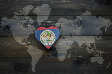 wooden heart with national flag of belize near world map on the wooden background.