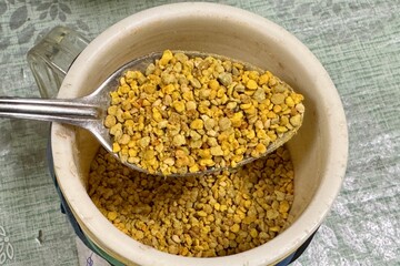 The seller's hand fills bee perga as called ambrosia in a plastic container. Top view. Close-up with a spoon in a container. Healthy eating. The energy of life