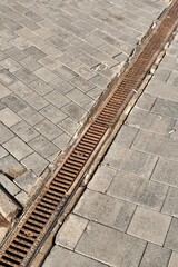 Iron grate of a drainage system for storm water drainage from a pedestrian sidewalk near a lawn. A...