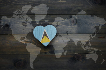 wooden heart with national flag of saint lucia near world map on the wooden background.