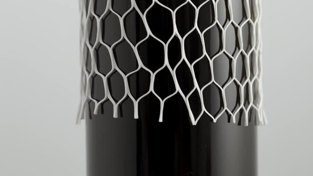 The soft protective transport net is removed from the wine bottle.